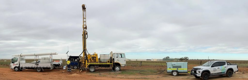 A number of trucks with a large drilling rig sink a bore