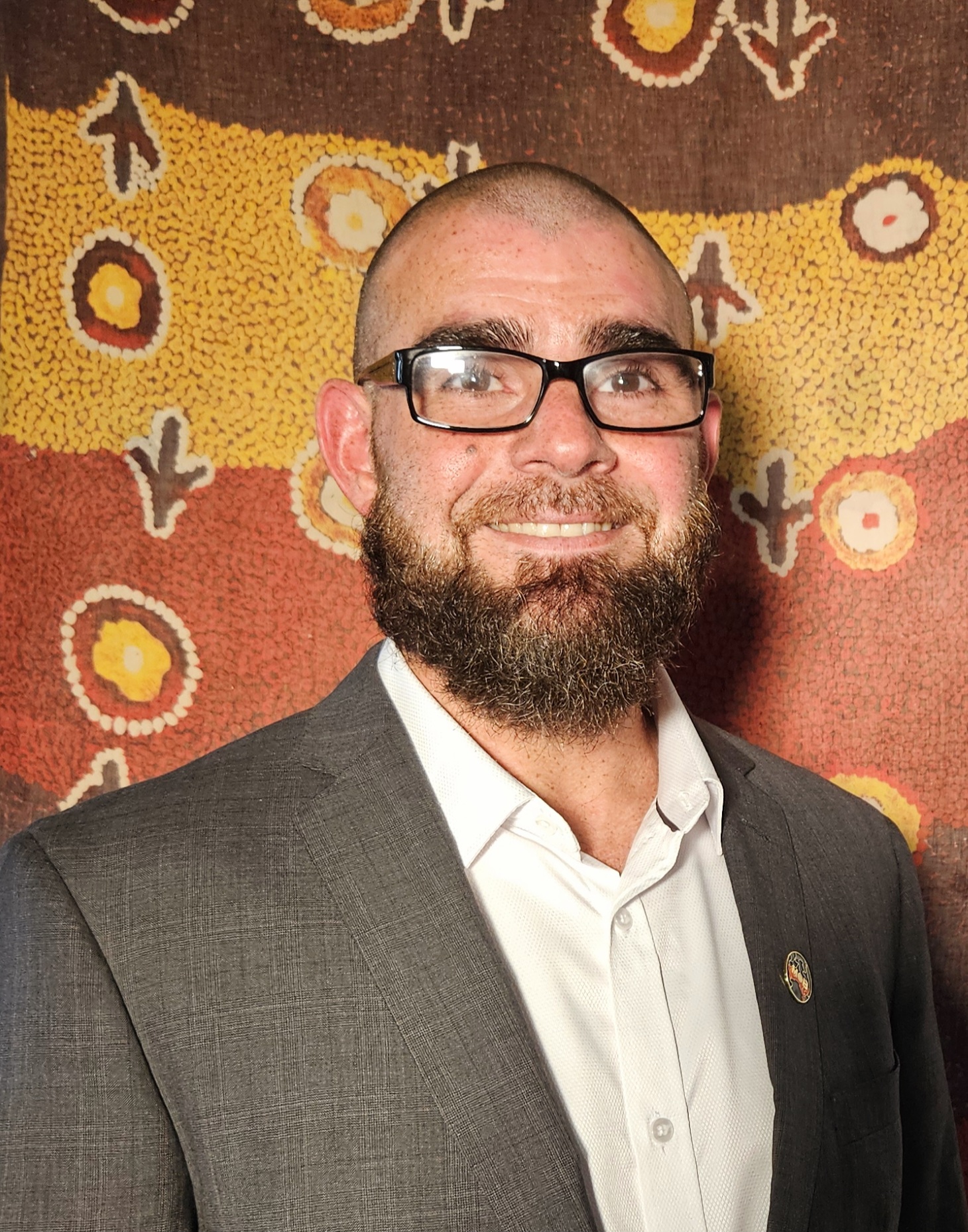 Troy Meston stands in front of a First Nations painting